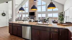 A spacious kitchen with dark wooden cabinets, a stainless steel dishwasher, and pendant lighting.