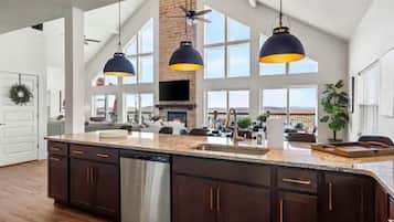 A spacious kitchen with dark wooden cabinets, a stainless steel dishwasher, and pendant lighting.