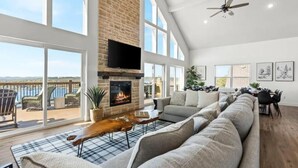 A spacious living room with a fireplace, large windows, and a view of the outdoors.