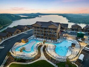 A hotel with a large swimming pool, a parking lot, and a view of a river. - Crane’s Nest-Year Round Private Pool & Hot Tub (kimberling City)