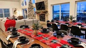 A dining area with a long table set for a meal, a Christmas tree, and a fireplace.