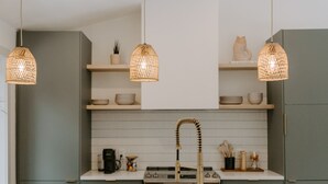 Una cocina moderna con iluminación colgante, un lavamanos y dos taburetes de bar.