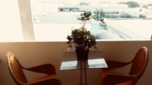 A balcony with two wicker chairs and a small glass table with a potted plant. - Navanakorn Aomsin Hotel near Big C Super (Khlong Luang)