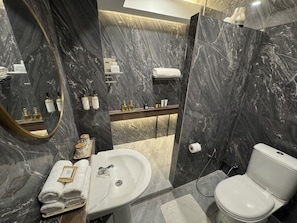 Ein modernes Badezimmer mit Marmorwand, Waschbecken, Toilette und Spiegel.