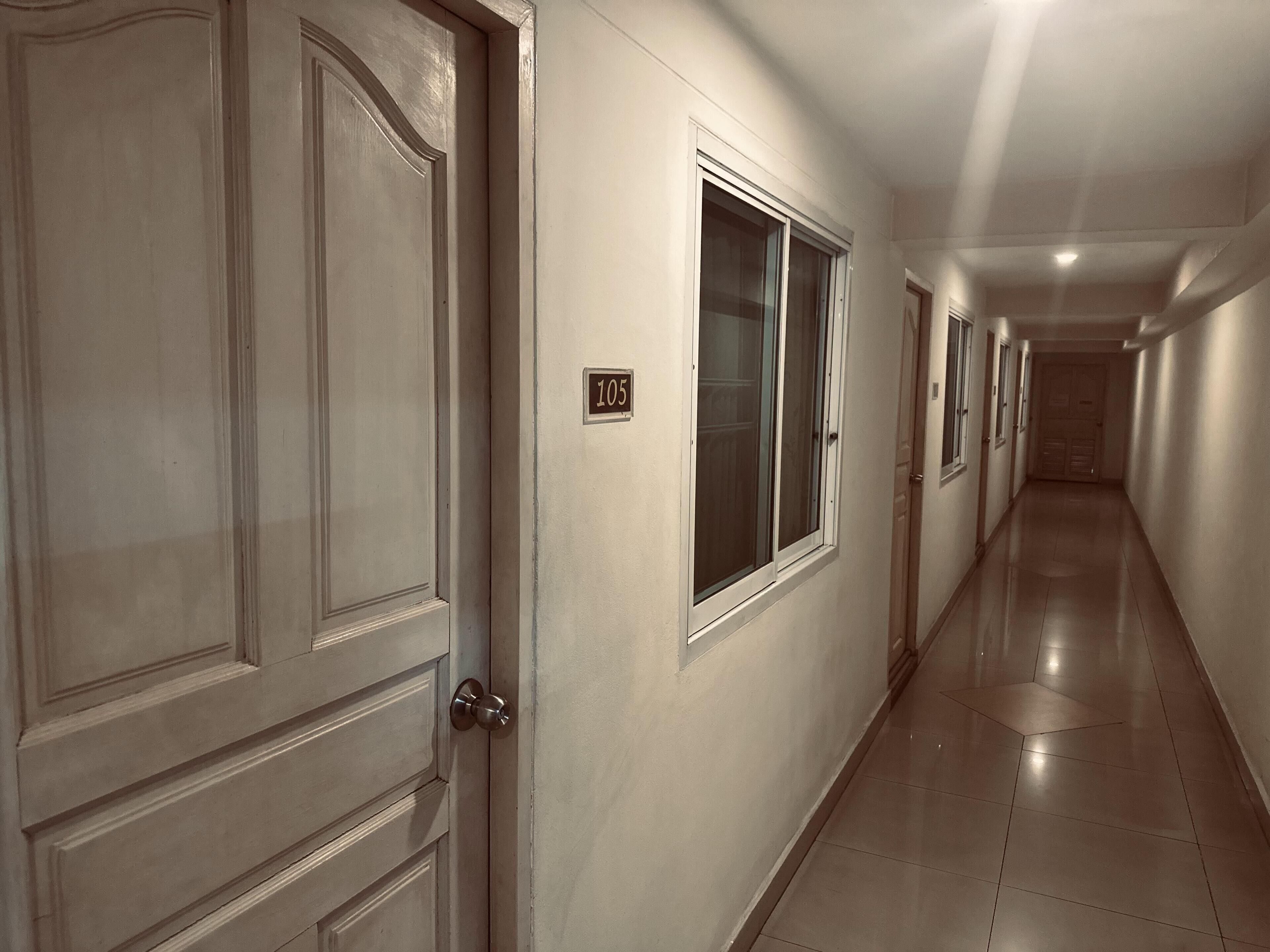 A hallway with doors, a number plate, and a tiled floor.