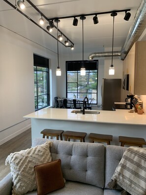 Una cocina moderna con una isla central, taburetes de bar e iluminación colgante.