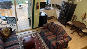 A compact living space with a sofa, a small rug, a dining table, and a kitchen area including a refrigerator and cabinets. - The Walnut at Hamilton Cove ~ Cabin Nineteen ~ Pet friendly ~ Lakefront (Royal)
