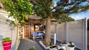 A patio area with a wooden table and chairs, a stone wall, and potted plants. - MOSCHATOS BEACH HOUSE (Καμάρι)