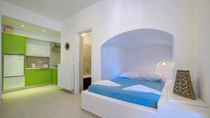 A compact hotel room with a bed, a kitchenette, and a bathroom. - MOSCHATOS BEACH HOUSE (Καμάρι)