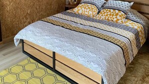 Et soveværelse med en køjeseng i træ, et vindue og et sengelagen med mønster.