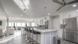 A modern kitchen with a central island, stainless steel appliances, and a ceiling fan. - Ocean View Poolside Retreat
 (Oceanside)
