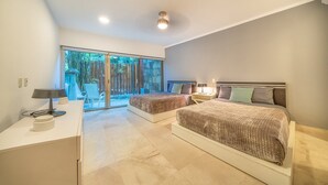 A modern bedroom with two beds, a desk, and a large sliding glass door leading to an outdoor area.