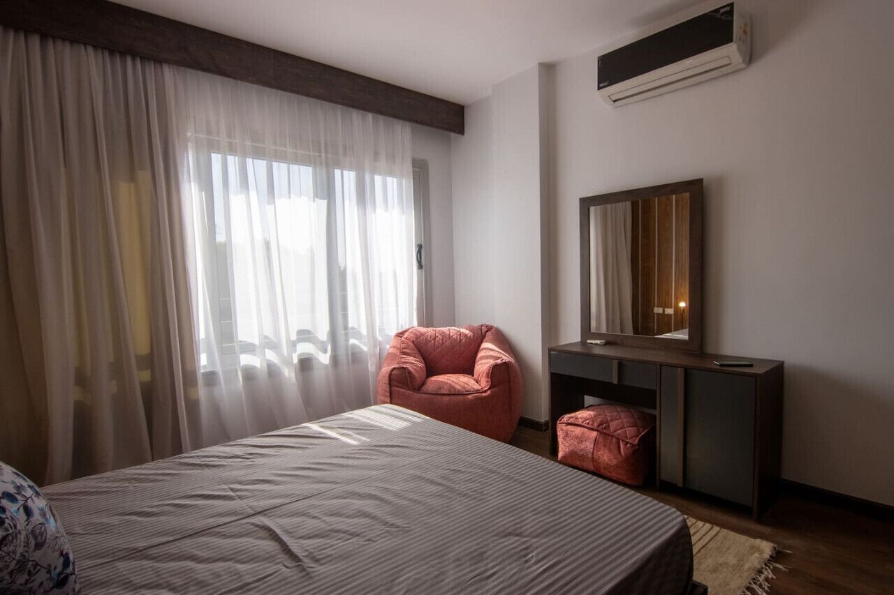 Une chambre à coucher avec un lit, une chaise, un bureau et un miroir.