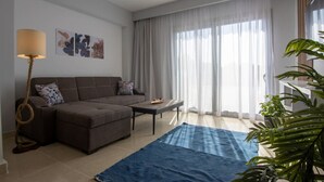 Una sala de estar moderna con un sofá, una mesa de centro, una lámpara y un ventanal con cortinas translúcidas.