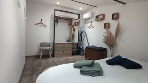 A modern bedroom with a bed, a dresser, a vanity, and a hanging closet.