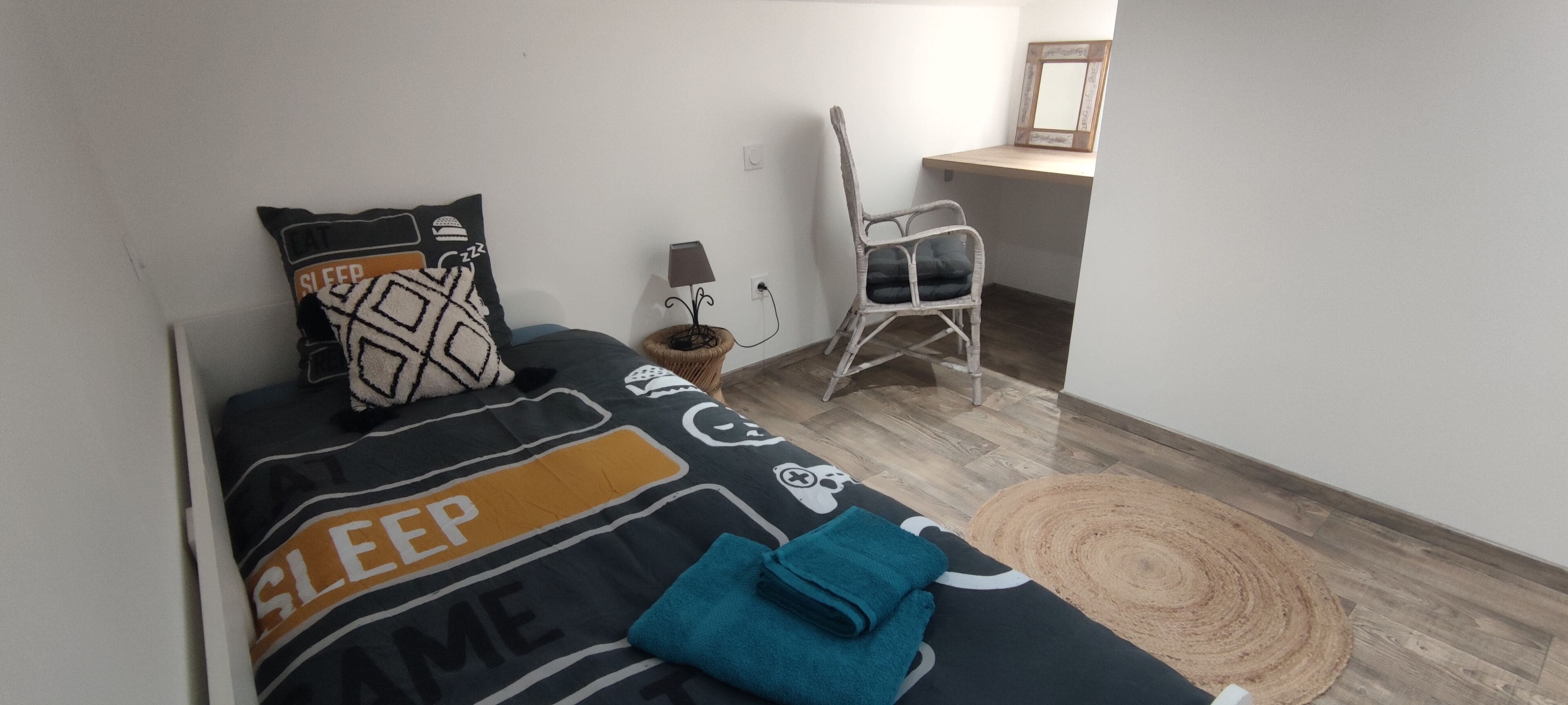 Une chambre à coucher avec un lit, des oreillers, une chaise, une lampe et une petite table.