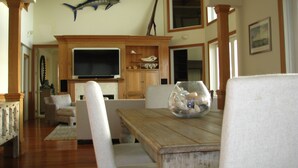 A living room with a wooden table, chairs, a fish tank, a television, and a large fish mounted on the wall. - Plantation at St George Island Fl.. Beautiful beach view from all bedrooms . (Saint George Island)