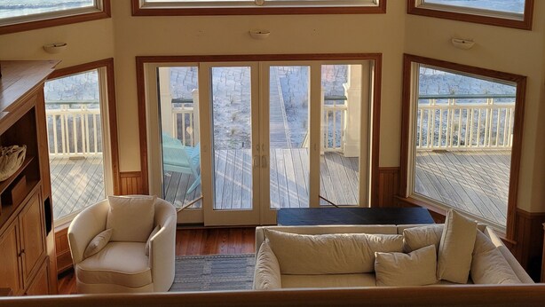 A spacious room with large windows overlooking the ocean, wooden ceiling beams, and a ceiling fan. - Plantation at St George Island Fl.. Beautiful beach view from all bedrooms . (Saint George Island)