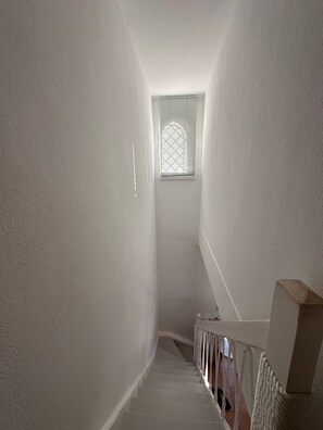 Stairwell with handrail and window with horizontal blinds.