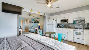 A bedroom with a bed, a ceiling fan, and a view into a living area with a sofa and a table. - Panama City Beach Getaway - Walk to Beaches! (Panama City)