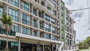Un hôtel à plusieurs étages au design moderne, doté de balcons à chaque niveau et d’un espace d’entrée abrité.