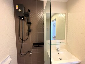 A bathroom with a glass-enclosed sink, a shower with a handheld showerhead, and a tiled wall. - Zcape2 apartment by Lofty (Choeng Thale)