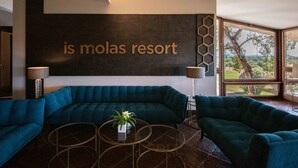 Ein modernes Wohnzimmer mit einem großen, blaugrünen Sofa, zwei runden Couchtischen und einem an der Wand befestigten Schild mit der Aufschrift 'is molas resort'.