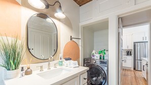 Ein modernes Badezimmer mit Waschbecken, Spiegel und Waschmaschine.