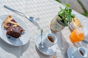 A table with a checkered tablecloth, a plate with a slice of pie, a cup of coffee, a small potted plant, and a glass of orange juice.