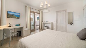 A bedroom with a bed, a desk, a chair, a television, and a view of the outdoors. - Residenza L'Alzoni (San Teodoro)
