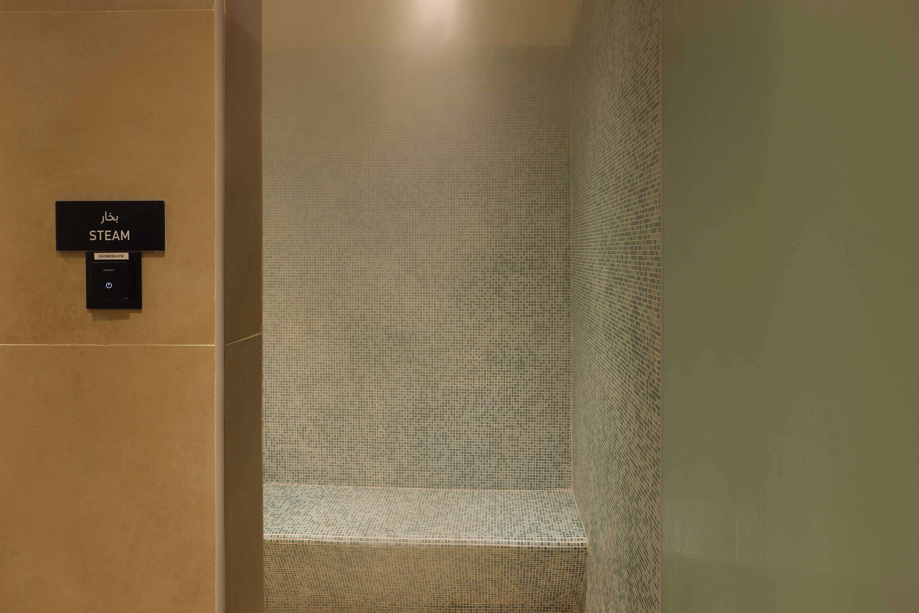 A steam room with a sign indicating its name and a control panel.