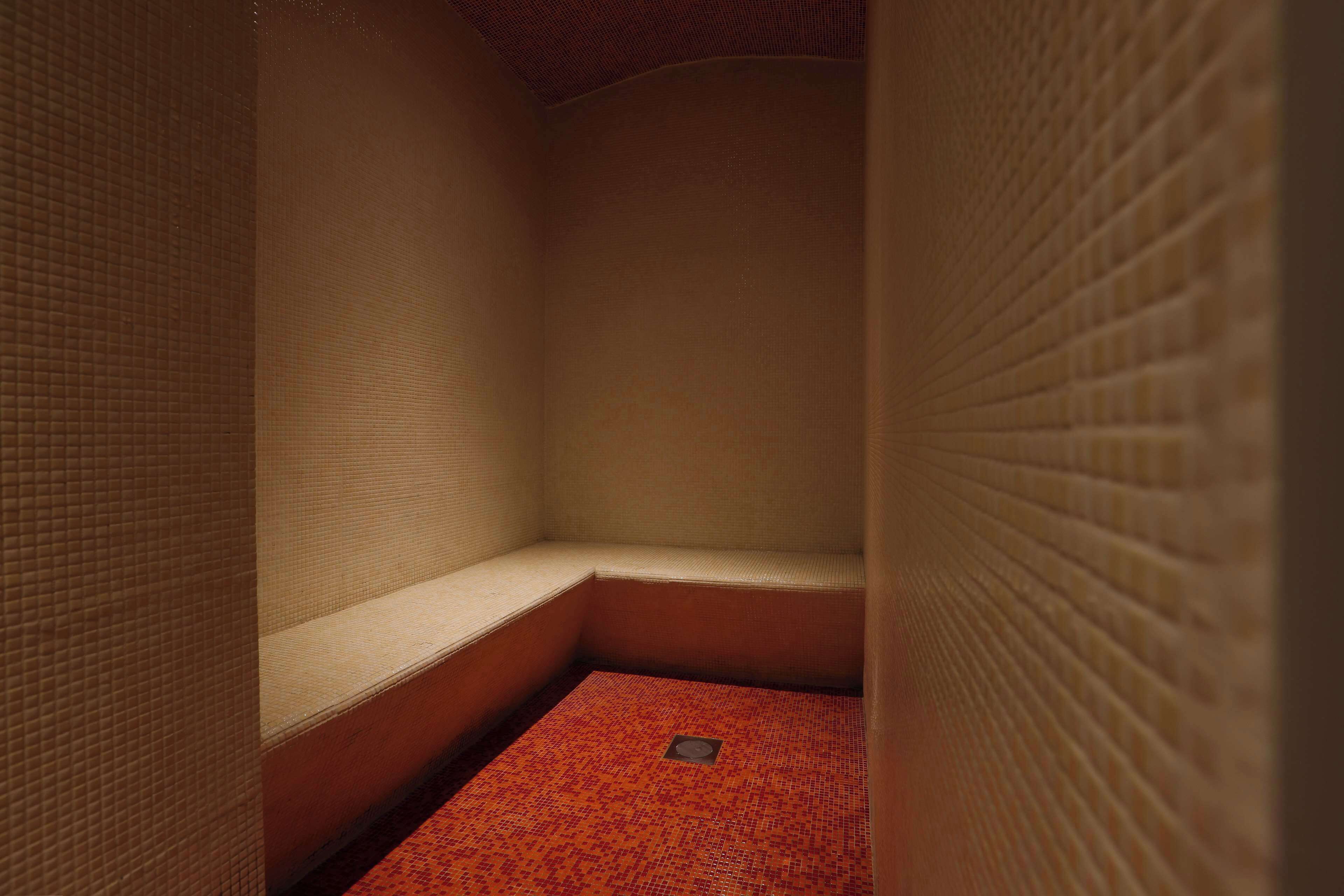 A small, enclosed room with a bench and a red patterned floor.