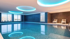 A modern indoor swimming pool with a clear blue water surface, surrounded by large windows offering views of the city. - Radisson Hotel & Residence Riyadh Olaya (Riyadh)