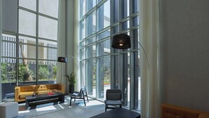 A modern living room with large windows, a sofa, a coffee table, and a lamp. - Radisson Hotel & Residence Riyadh Olaya (Riyadh)