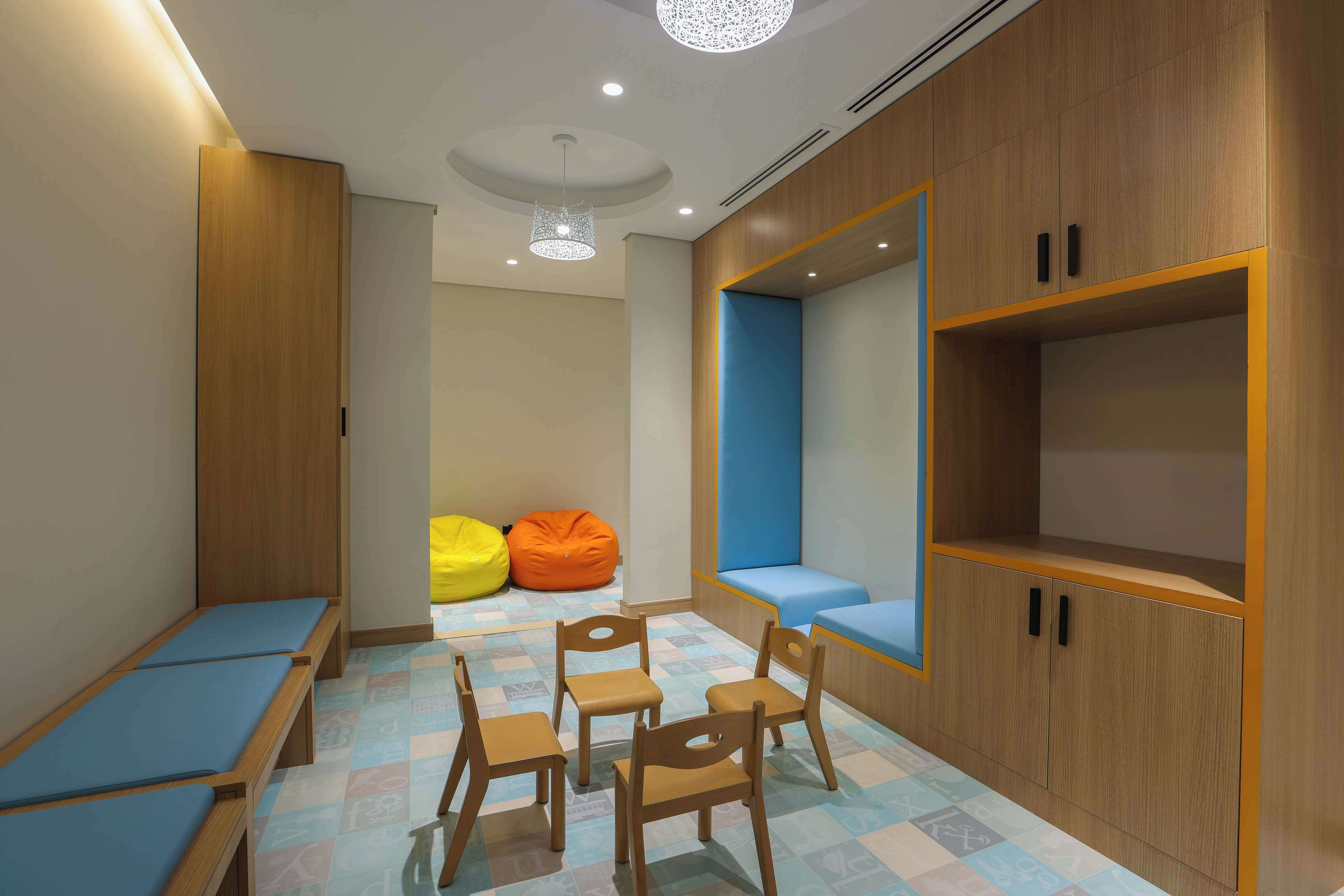 Una sala de juegos infantil con asientos, un espejo grande y un armario de madera.