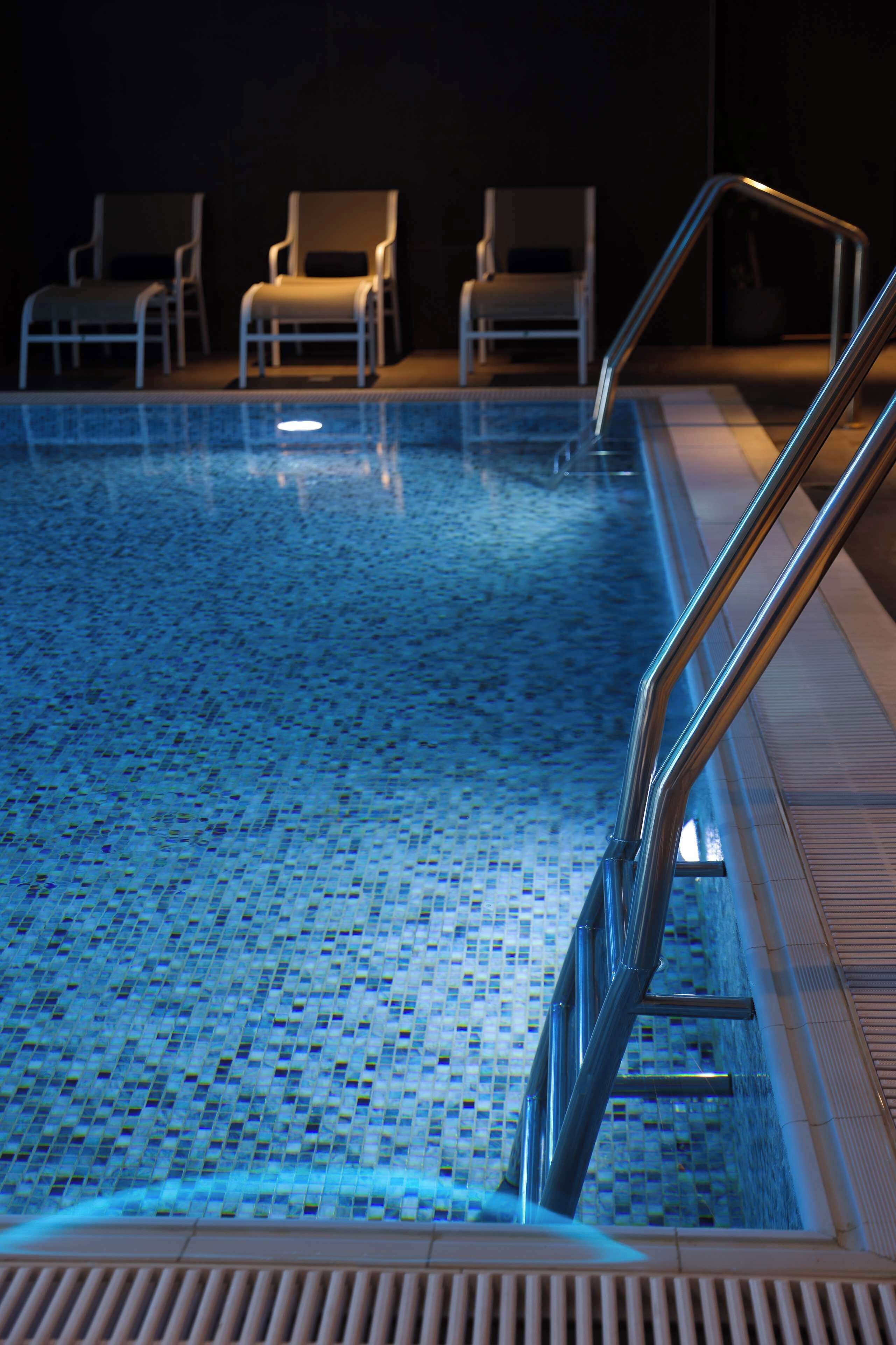 A swimming pool with a tiled floor and metal handrails.