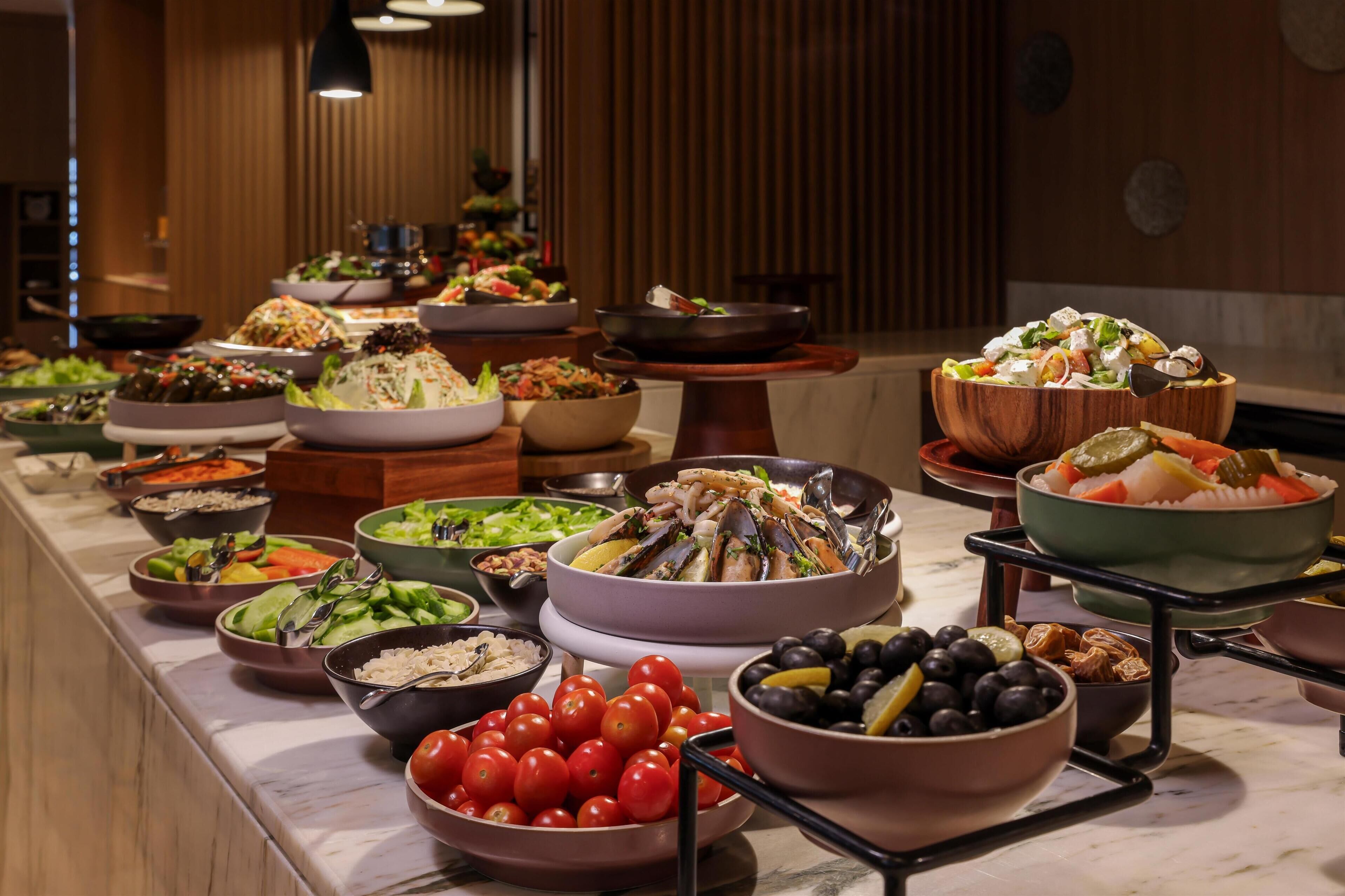 Un bufé con diversos platos, incluyendo mariscos, ensaladas y frutas.