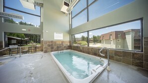 A spa area with a hot tub, large windows, and a view of buildings. - Pet-friendly condo w/ balcony, hot tub & gym (Winter Park)
