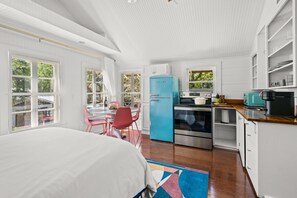 Cocina compacta con refrigerador azul, estufa y microondas. Hay una zona de comedor con una mesa y sillas.