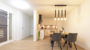 A modern kitchen with white cabinets, a wooden countertop, and a dining area with a table and chairs.