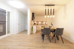 Una cocina moderna con armarios blancos, encimera de madera y un comedor con mesa y sillas.