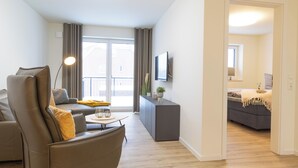 A modern living room with a sofa, a coffee table, and a TV mounted on the wall.
