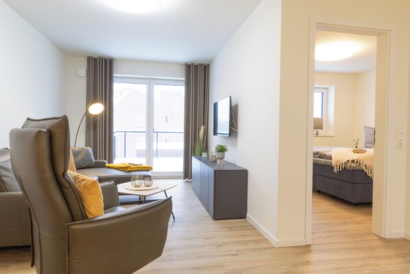A modern living room with a sofa, a coffee table, and a TV mounted on the wall.