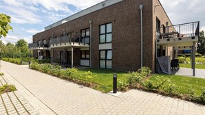A modern brick building with a flat roof, large windows, and a covered outdoor seating area.