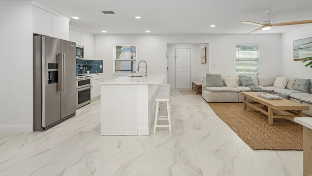 A modern kitchen with white cabinetry, a stainless steel refrigerator, and a central island.
