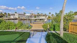 A waterfront property with multiple houses connected by docks, a wooden walkway, and lush greenery.