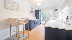 A modern kitchen with a central island, bar stools, and a view to the outdoors.