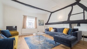 A living room with a dark blue sofa, yellow armchair, and a blue rug.