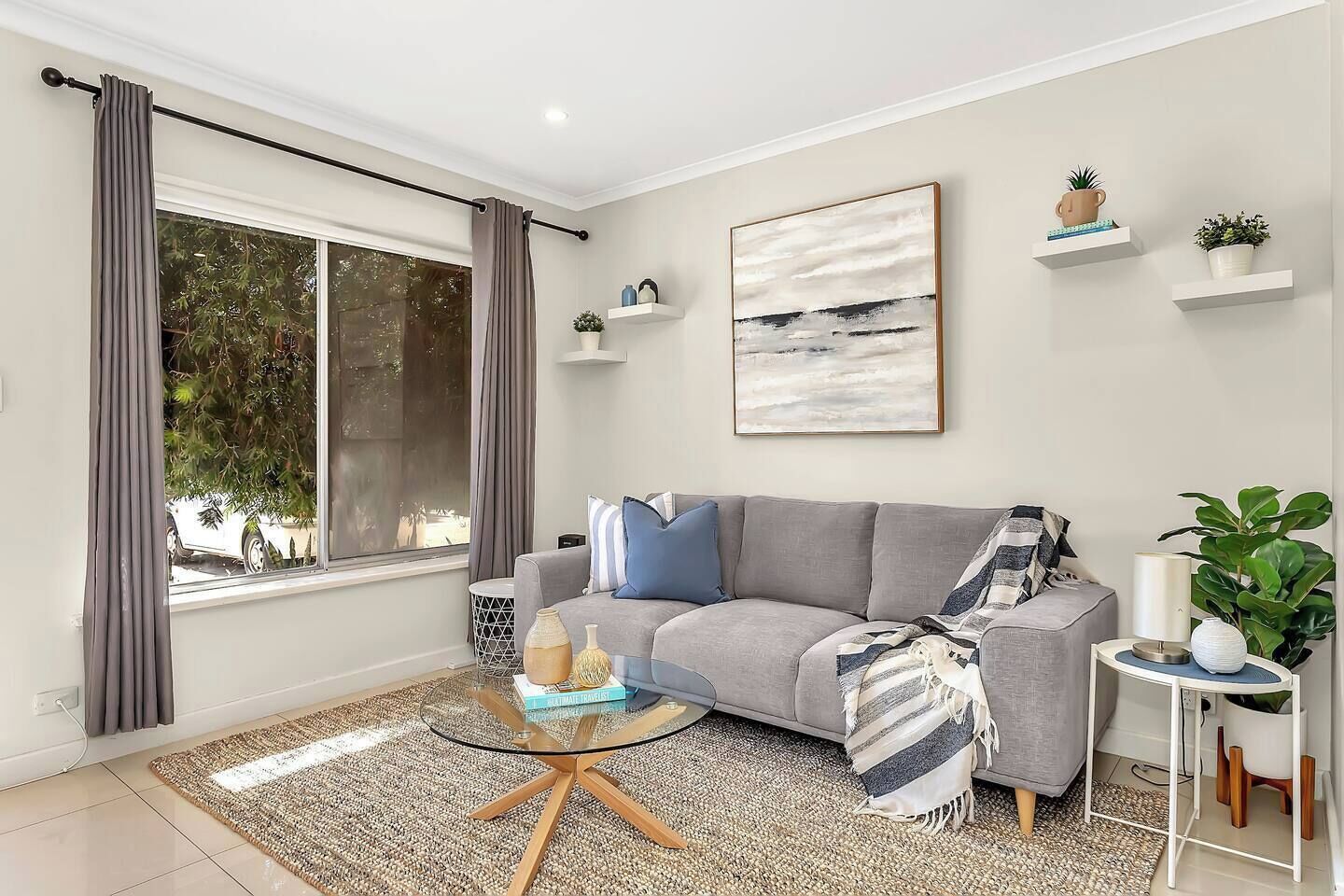Lounge in the living area with a comfy grey sofa, greenery touches, and a bright, inviting atmosphere for relaxing or socialising.