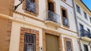 A multi-story building with balconies, a closed shutter, and a street lamp. - Casa Ideal Para Familias, Amigos, Celebraciones. Estupenda Ubicación y Zona (Chella)